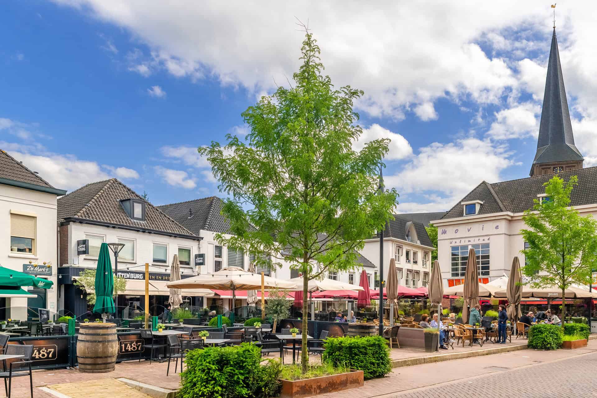 Gezellige terrassen en winkels op 't Gelders Eiland onder een heldere blauwe hemel.