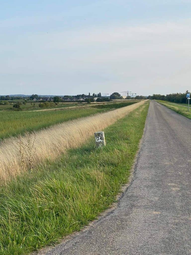 Rustige landelijke weg op 't Gelders Eiland met groene velden en een heldere hemel.