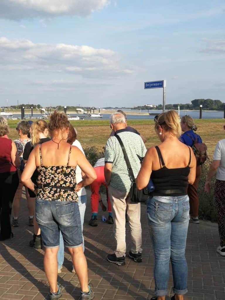 Groep toeristen bij 't Gelders Eiland met uitzicht op de rivier.