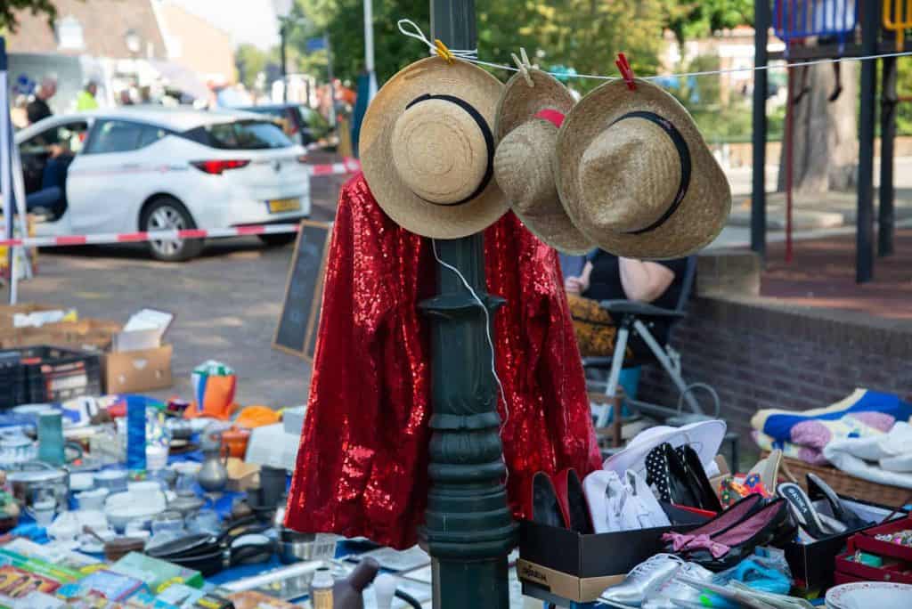 Hoedjes en kleding op een markt in 't Gelders Eiland, met diverse tweedehands spullen en koopwaar op.