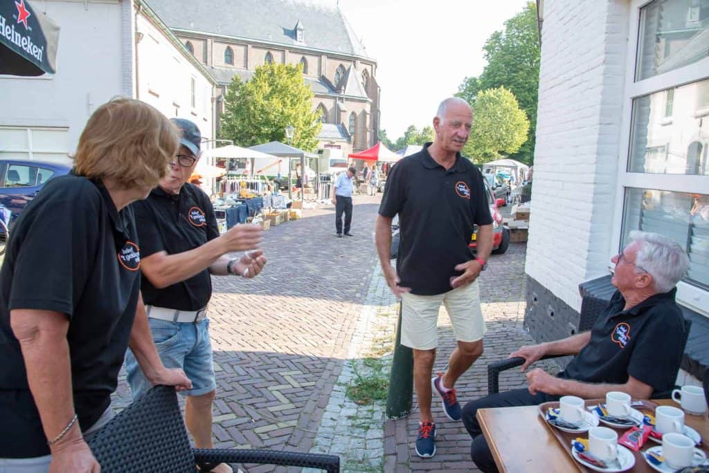 Gezellige ontmoeting van vier mensen op een terras in 't Gelders Eiland, genietend van koffie en ges.