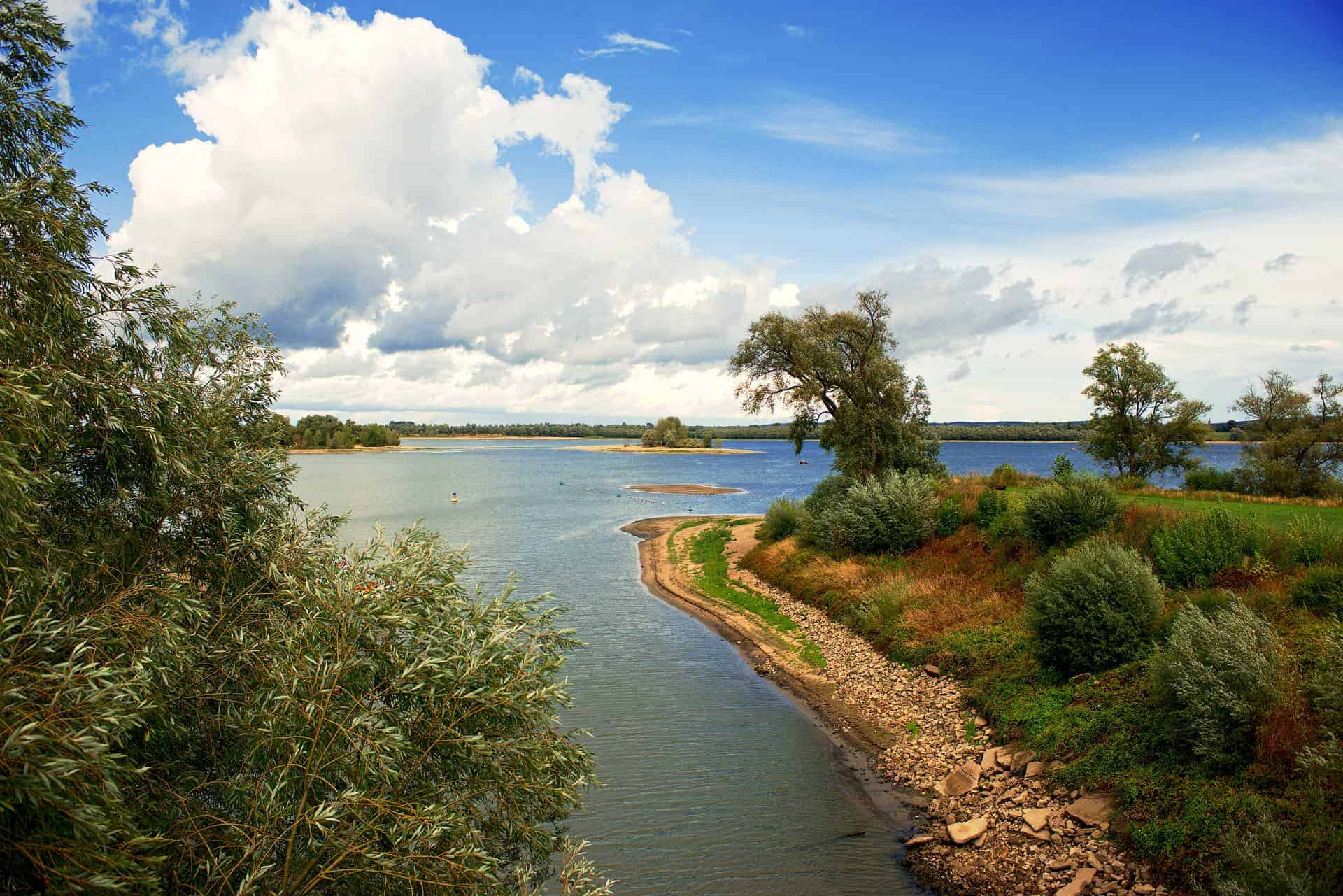 Gelders Eiland landschap met rivier en bomen, onder een partly bewolkte hemel, ideaal voor natuurlie.