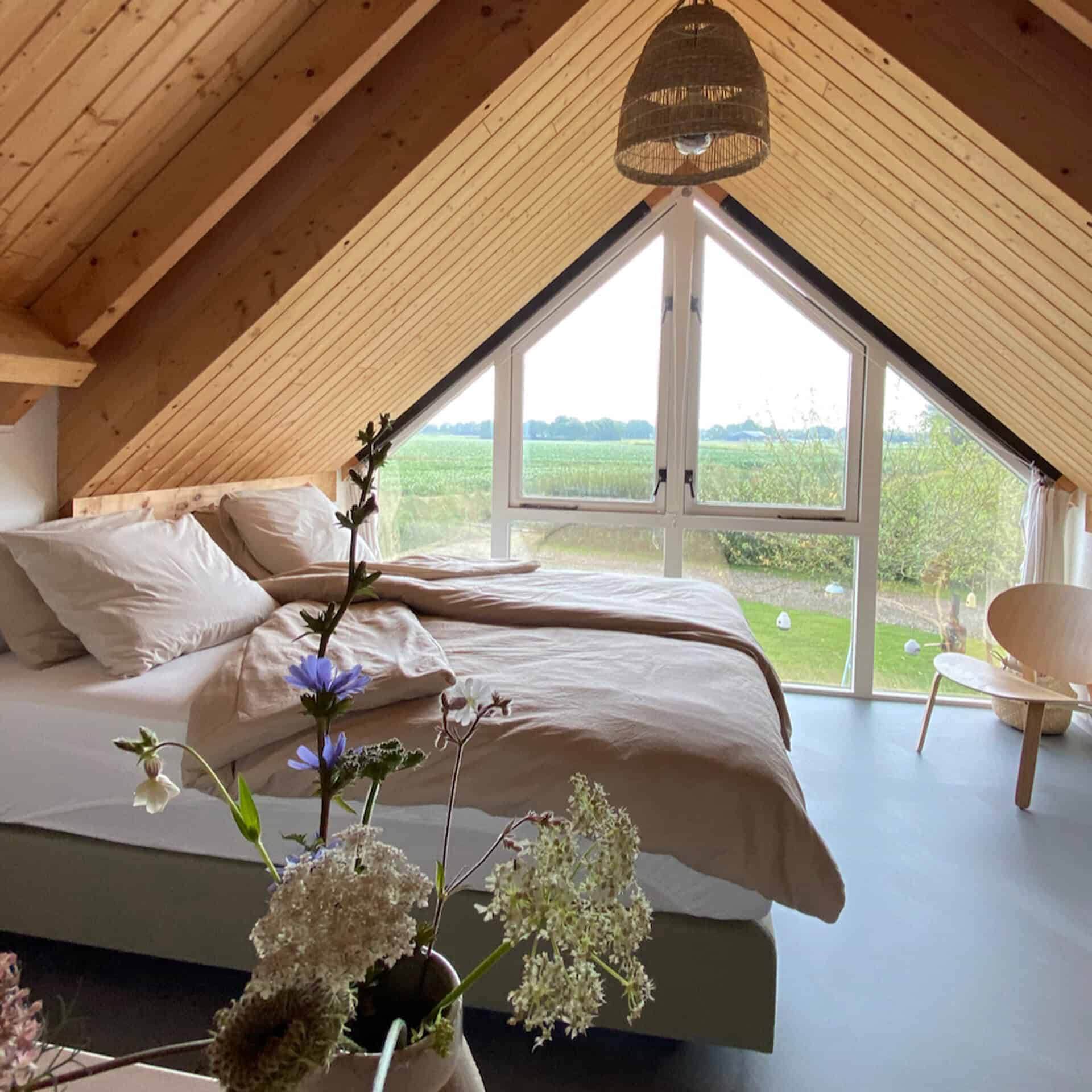 Slaapkamer met groot raam en uitzicht op groene omgeving op 't Gelders Eiland.
