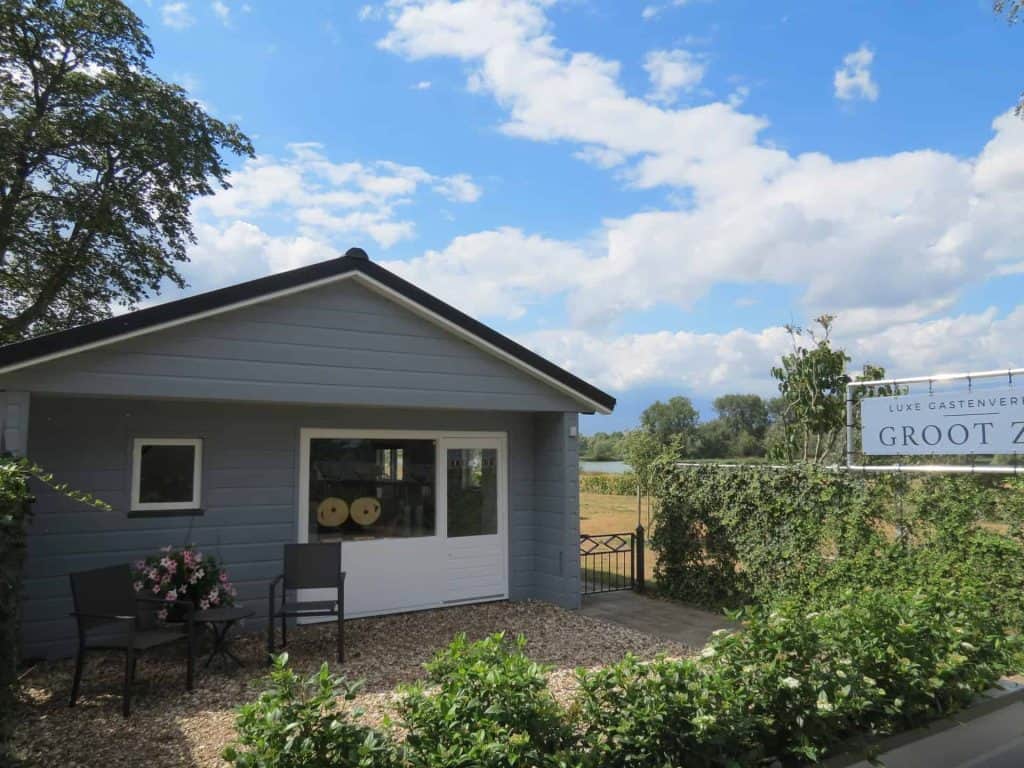 Huisje op 't Gelders Eiland met tuin en zitplaatsen onder een blauwe hemel.