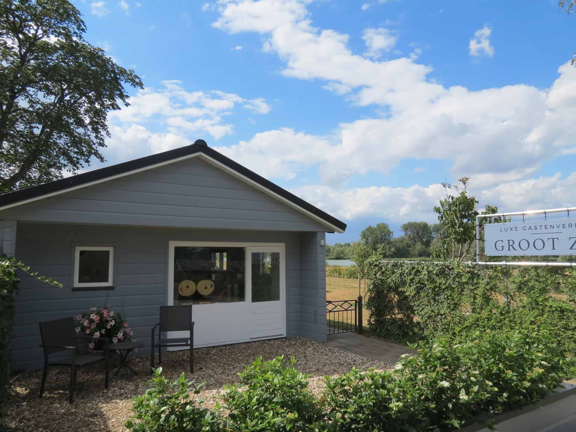 Huisje op 't Gelders Eiland met tuin en zitplaatsen onder een blauwe hemel.