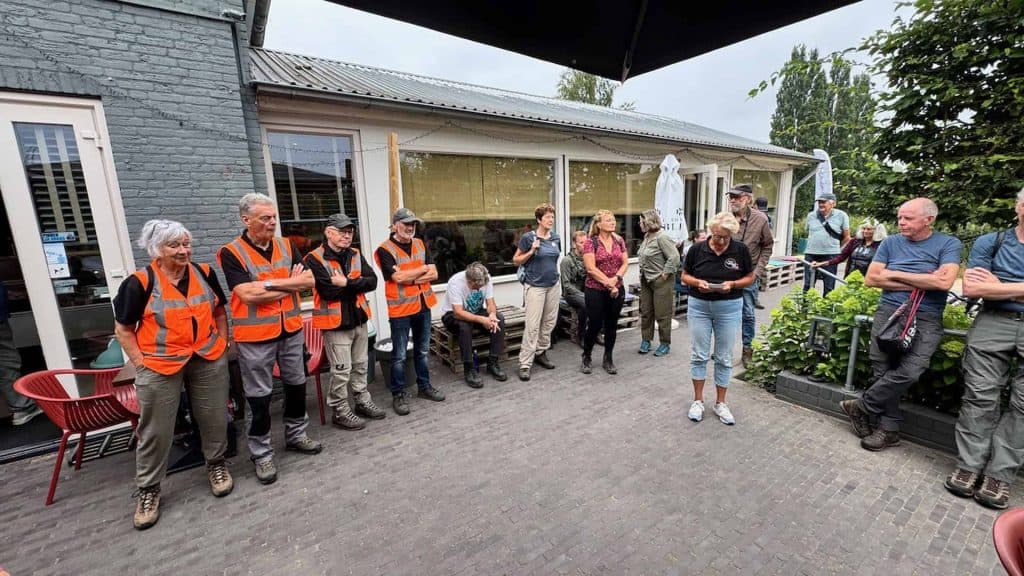 Gezelschap mensen tijdens een groepsactiviteit op 't Gelders Eiland, buiten onder een parasol.