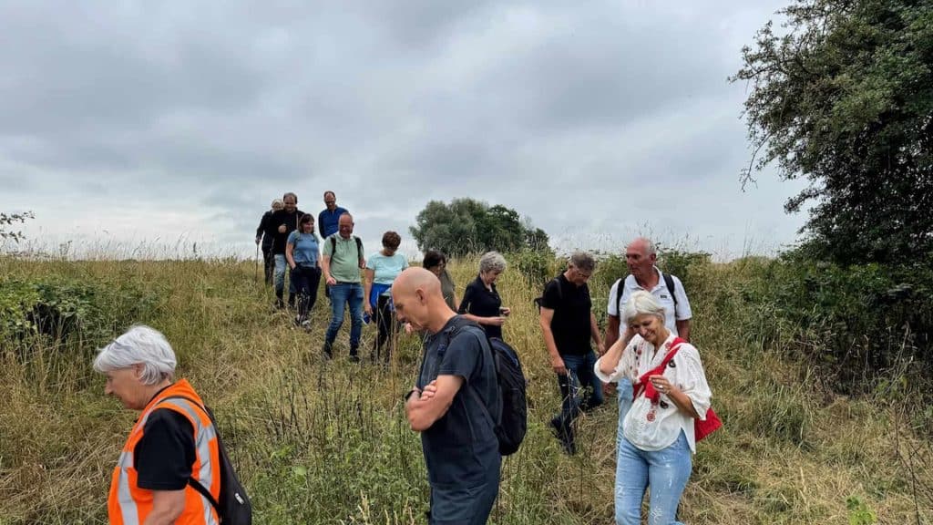 Zicht op wandelende mensen op 't Gelders Eiland in een natuurlijke omgeving onder een bewolkte hemel.