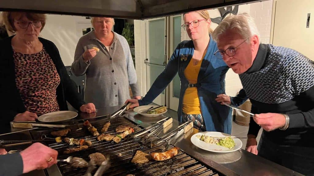Vijf mensen genieten van een kegelavond met gegrilde gerechten.
