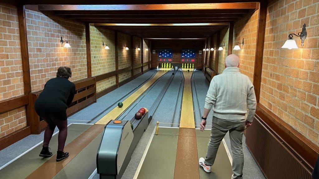 Mensen spelen kegelen in een gezellige binnenruimte met bakstenen muren.