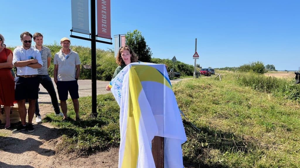 Vrouw onthult vlag op 't Gelders Eiland tijdens open dag.