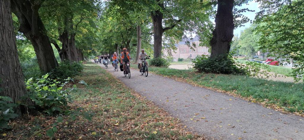 Vrijwilligers fietsen door een groen park op 't Gelders Eiland.