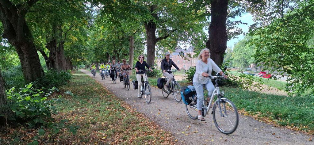 Groep vrijwilligers fietst door een groen park op 't Gelders Eiland.