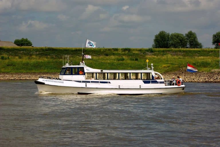 Passagiersboot op de Rijn met vlaggen, omgeven door groene oevers.
