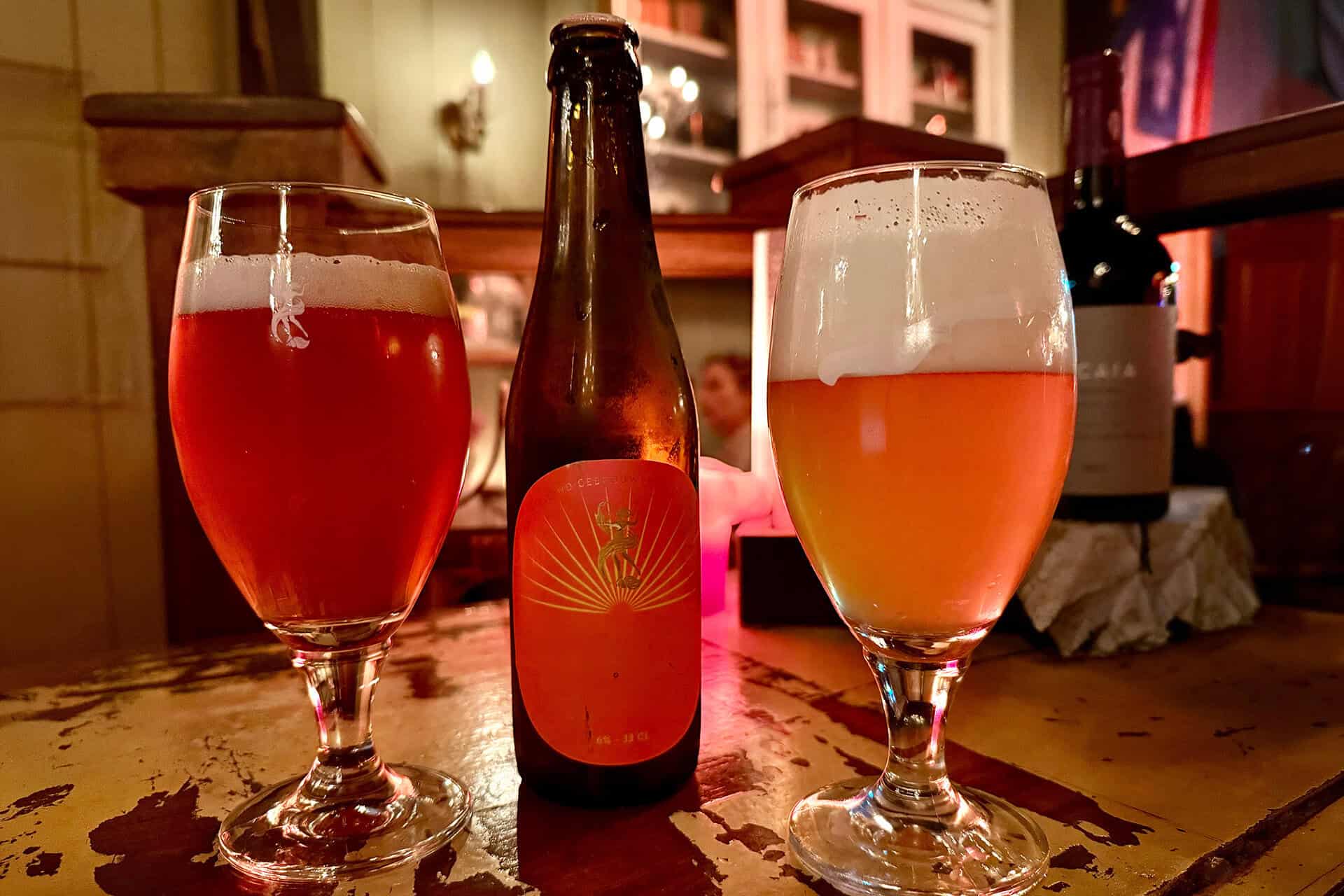 Twee glazen met bier en een bierfles op een houten tafel.