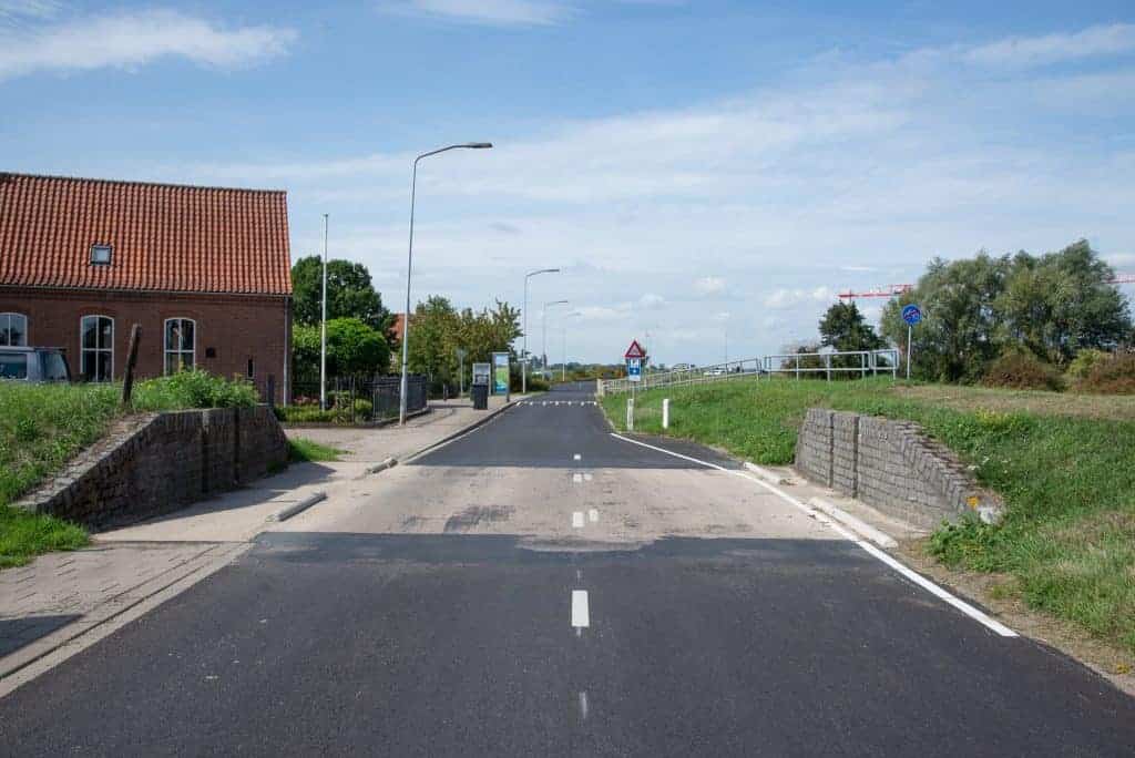 Rustige weg in een dorp op 't Gelders Eiland met brug en groene omgeving.