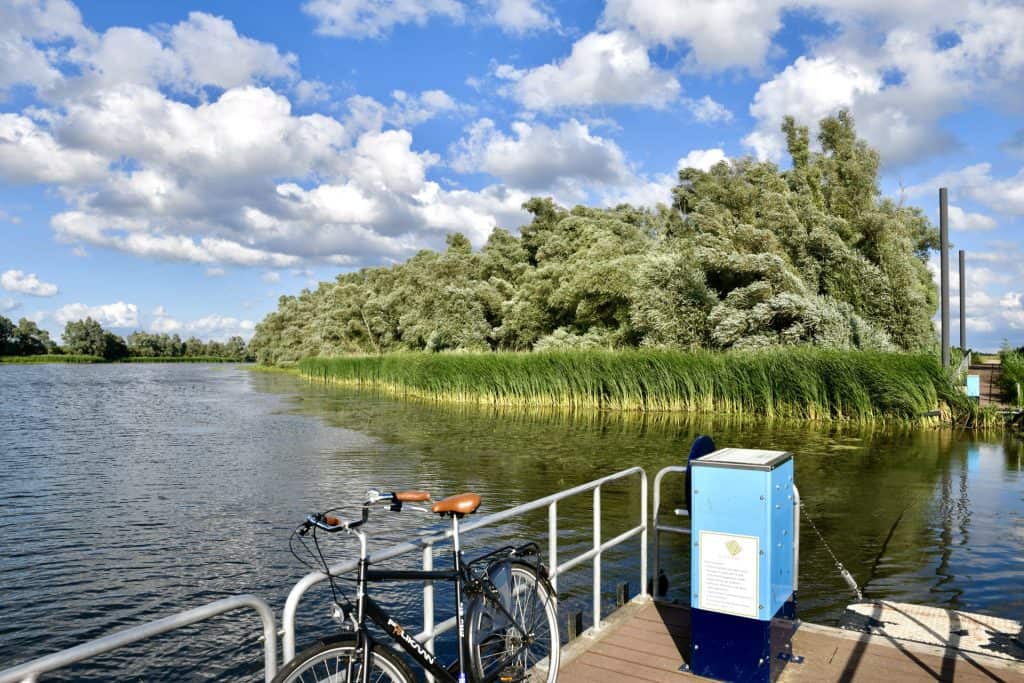 Rustige rivier met groene oevers en een fiets op de kade.