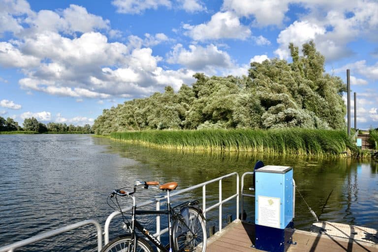 Rustige rivier met groene oevers en een fiets op de kade.