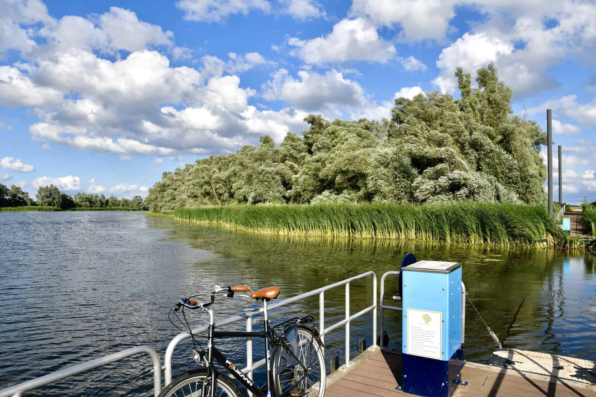 Rustige rivier met groene oevers en een fiets op de kade.
