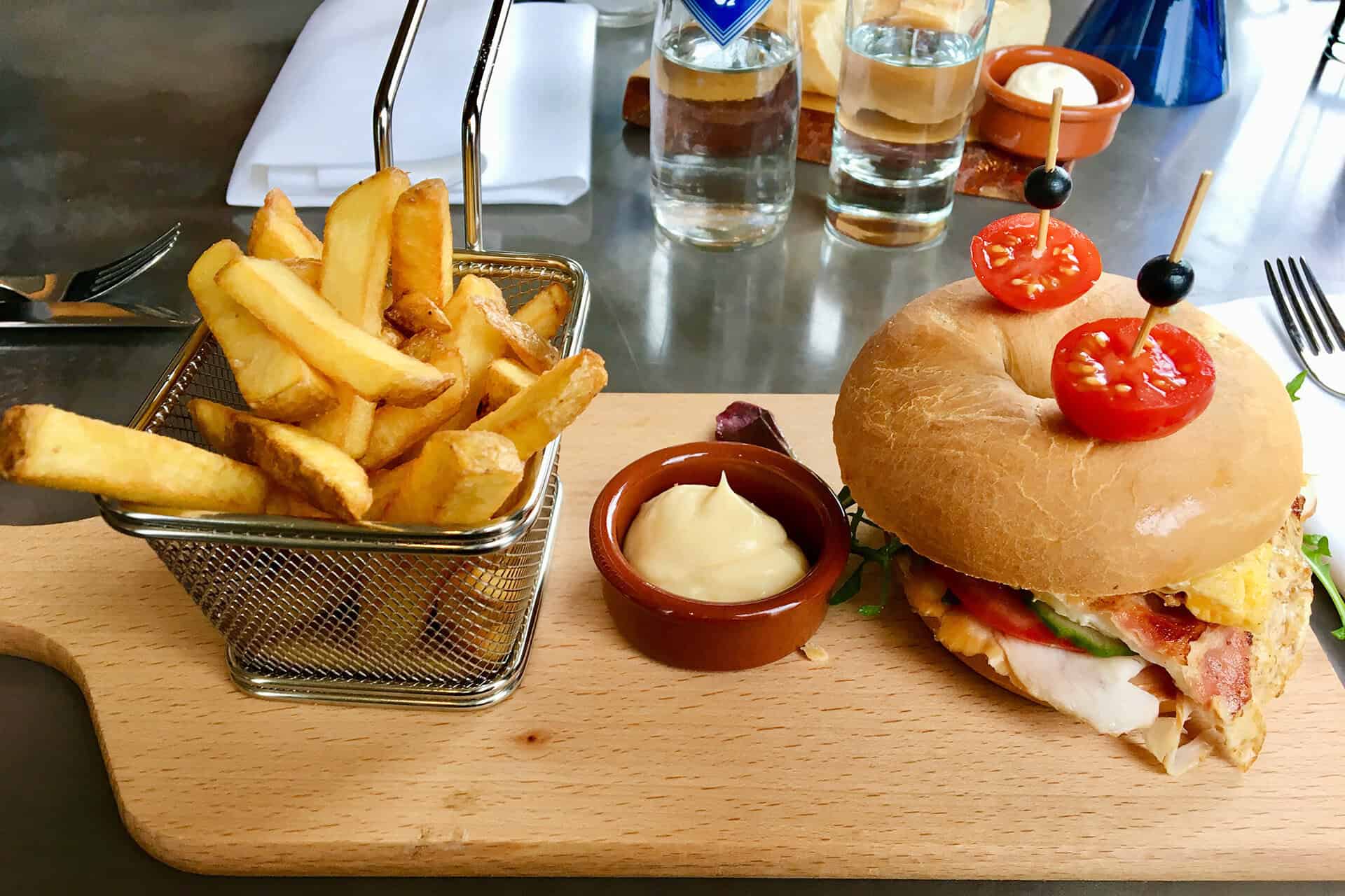 Gevulde burger met friet en saus op houten bord, 't Gelders Eiland.