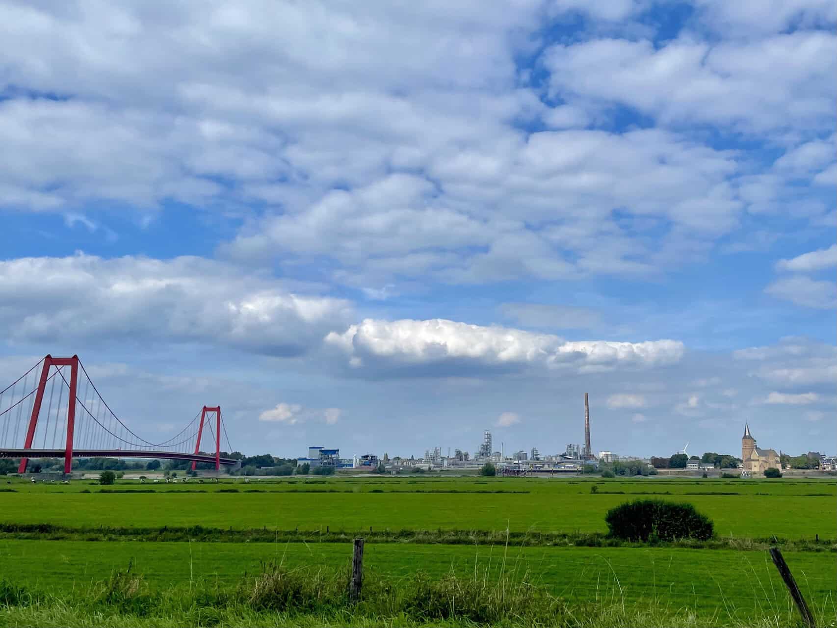 Uitzicht op de skyline van 't Gelders Eiland met brug en groene velden.