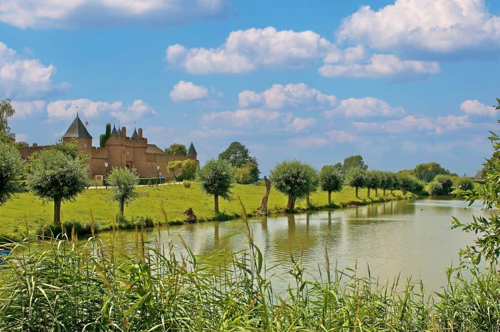 Kasteel aan de rivier op 't Gelders Eiland onder een blauwe hemel.
