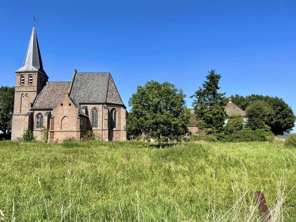 Historische kerk op 't Gelders Eiland met groene omgeving en blauwe hemel.