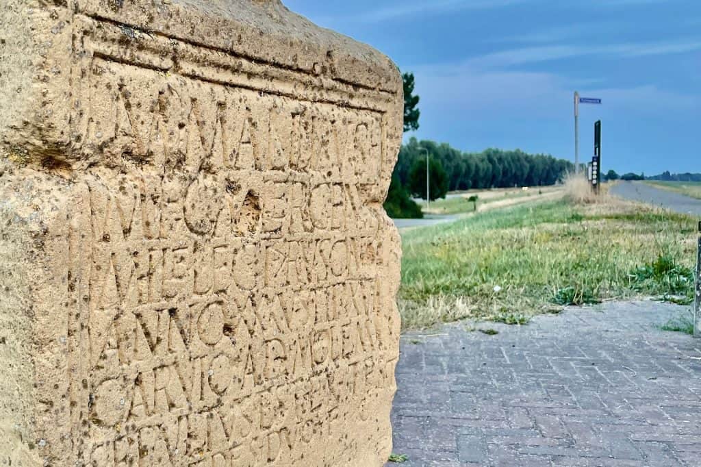 Oud stenen monument op 't Gelders Eiland met inscripties en uitzicht op de rivier.