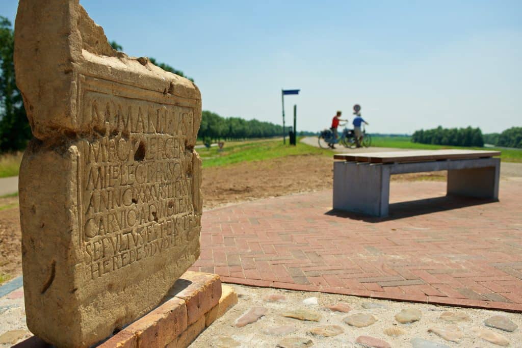 Historisch monument en fietspad op 't Gelders Eiland met twee fietsers in de achtergrond.