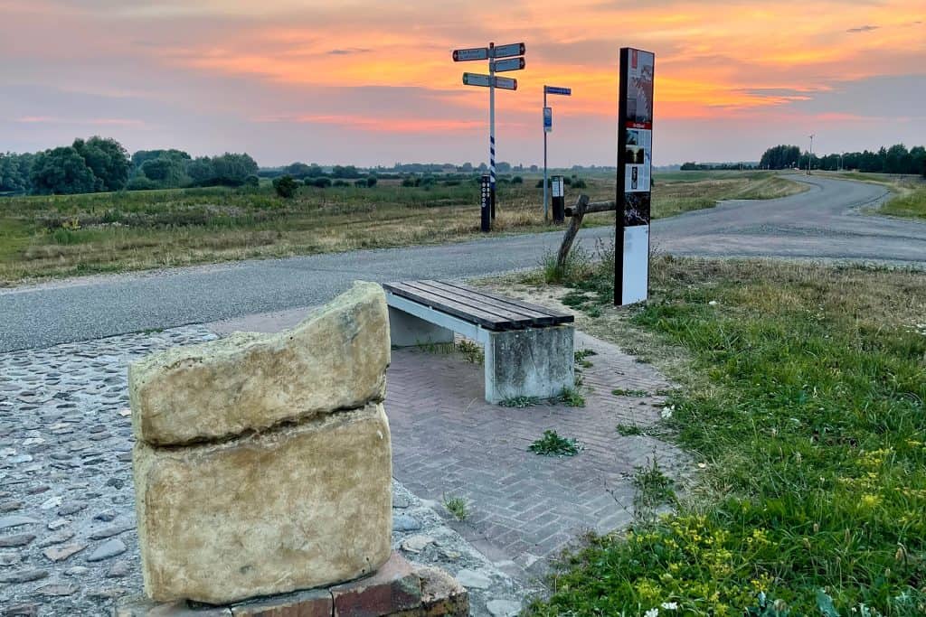 Zonsondergang over 't Gelders Eiland met bankje en route-informatie.