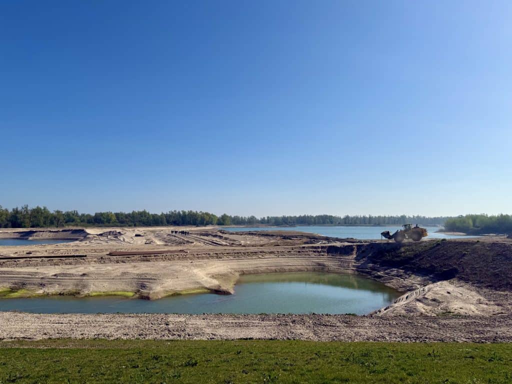 Uitzicht op Gelders Eiland met waterpartijen en natuur onder een heldere blauwe hemel.