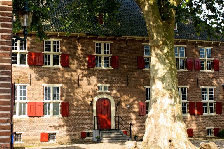 Historisch huis met rode luiken en grote boom op 't Gelders Eiland.