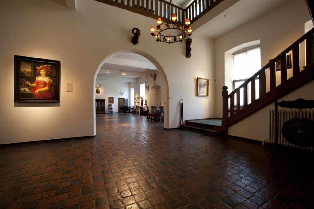 Binnenkant van Kasteel Huis Bergh met trap en schilderijen.