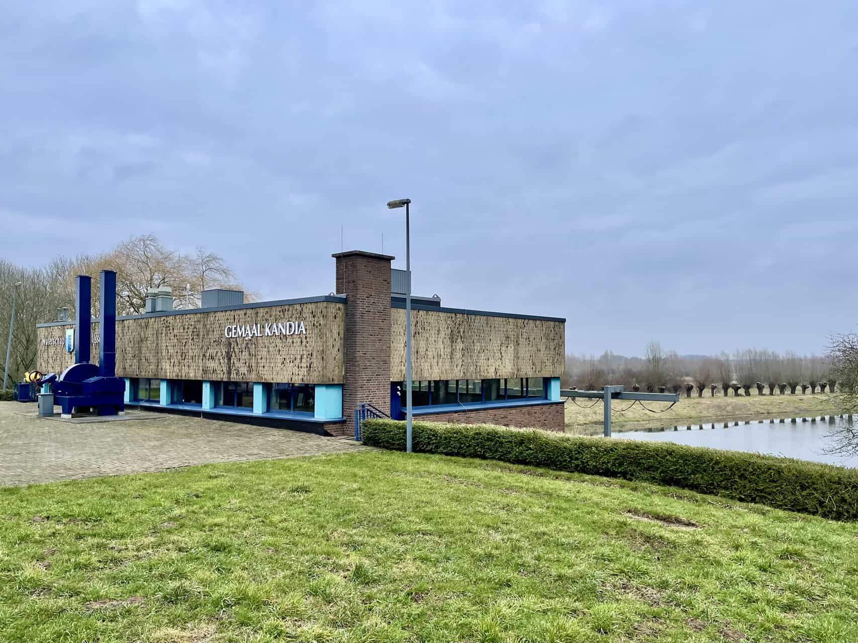 Modern gebouw aan water met groen gras en wandelpad, 't Gelders Eiland.