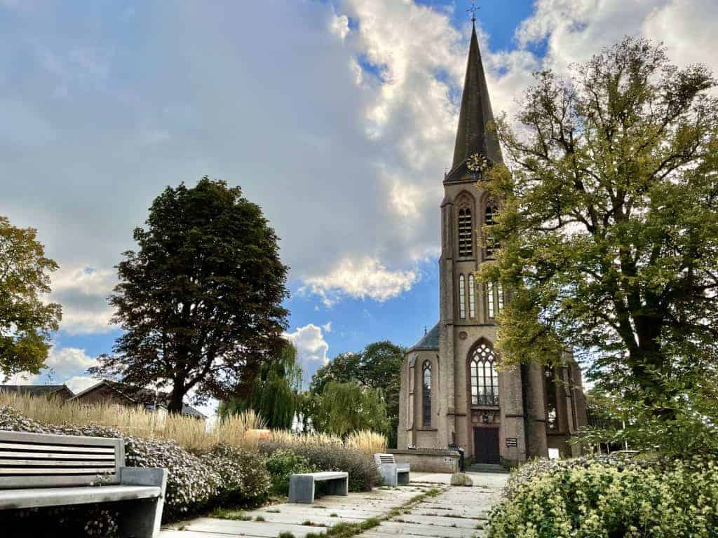 Kerk op 't Gelders Eiland met tuin, bomen en een heldere hemel.