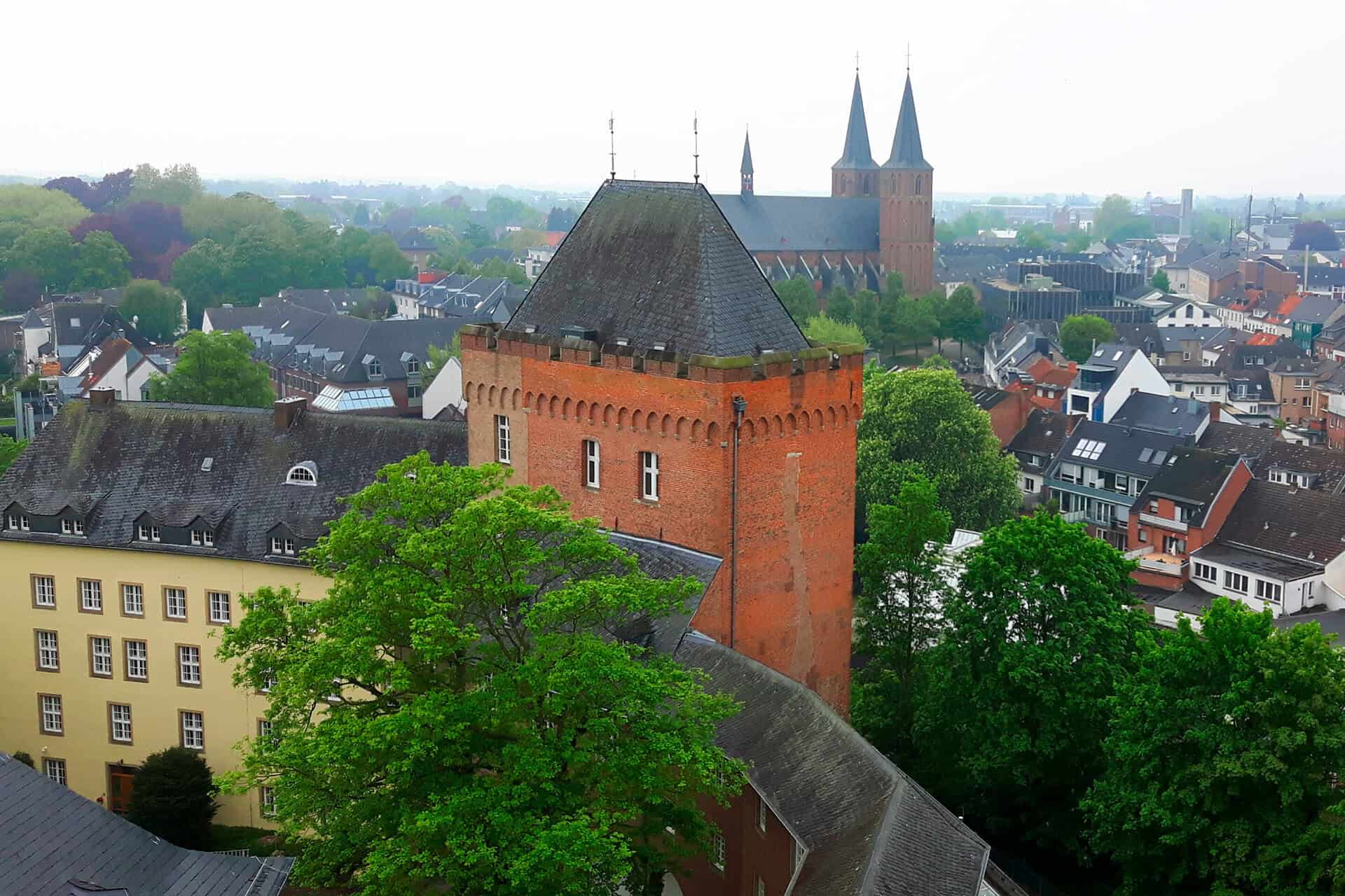 Kasteel op 't Gelders Eiland met groene bomen en stad op achtergrond.
