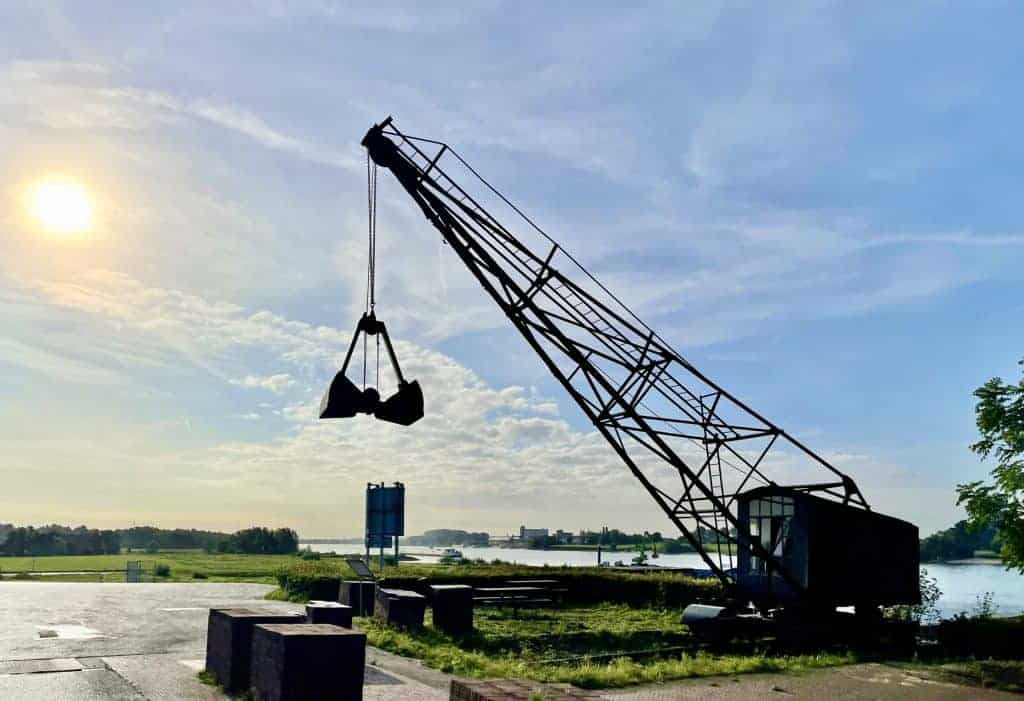 Oude kraan langs de rivier op 't Gelders Eiland met blauwe lucht en zonsondergang.