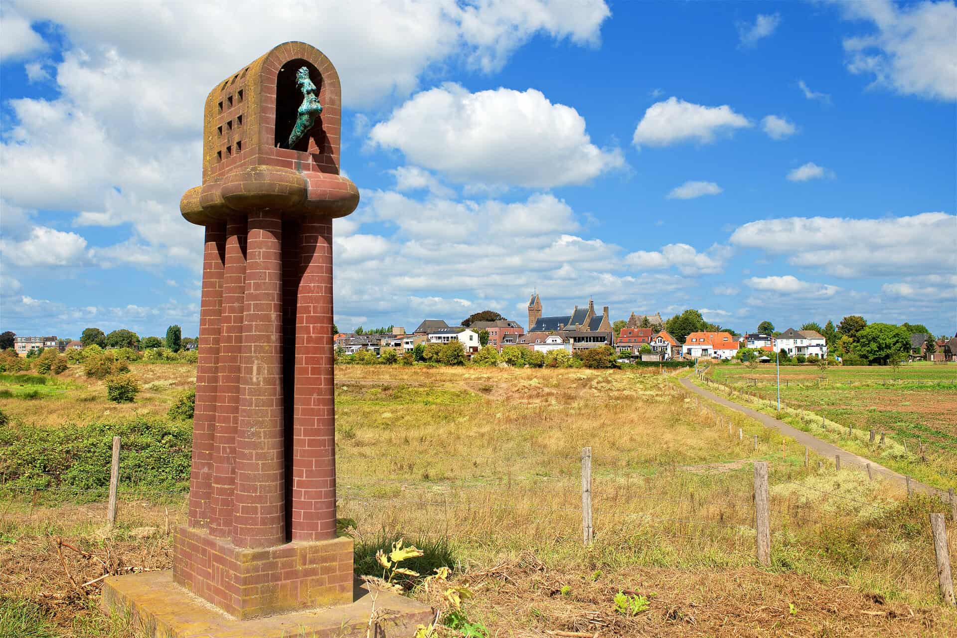 Monument op 't Gelders Eiland met uitzicht op dorp en landschap.