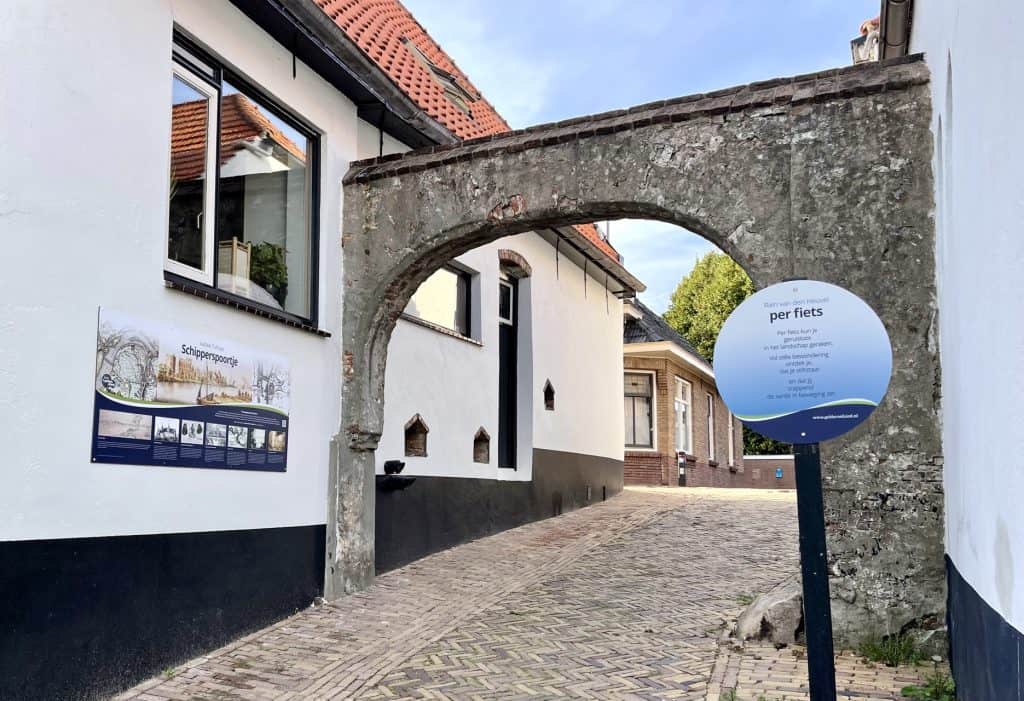 Oude stenen poort met straat en informatiebord op 't Gelders Eiland.