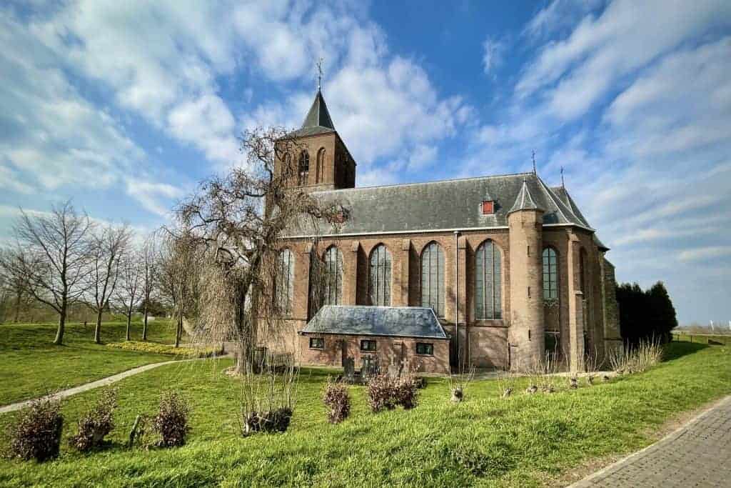Historische kerk op 't Gelders Eiland met blauwe lucht en groene omgeving.