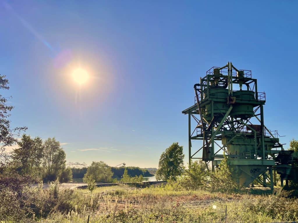 Industrieel gebouw met stalen structuur onder een heldere blauwe hemel.