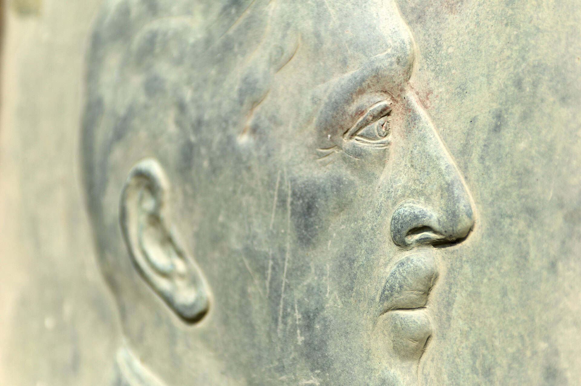 Zicht op een bronzen beeld van een man op 't Gelders Eiland, met focus op het profiel en details van.