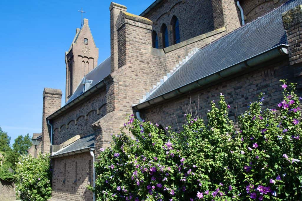 Historische kerk op 't Gelders Eiland met bloemen en blauwe lucht.