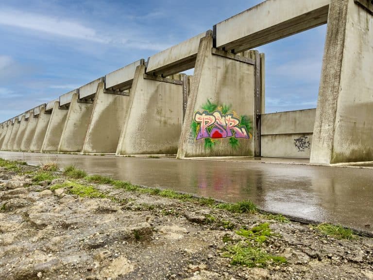 Waterkering op 't Gelders Eiland met graffiti kunst en blauwe lucht.