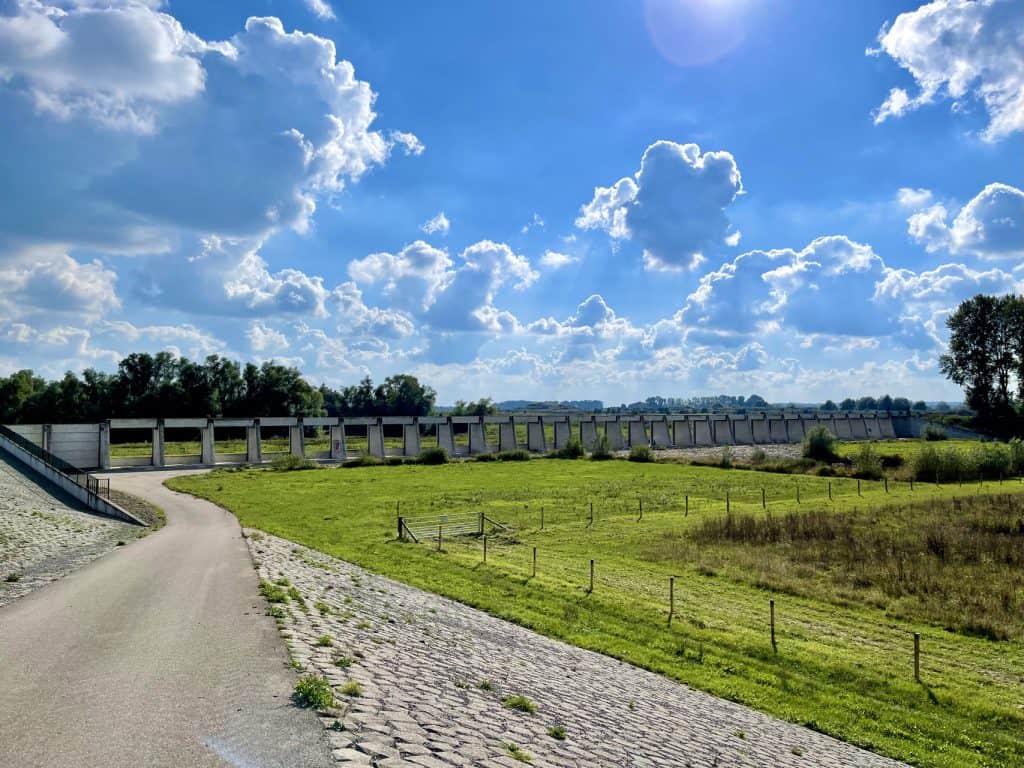 Uitzicht op Gelders Eiland met waterkering en groene weilanden onder een blauwe hemel.