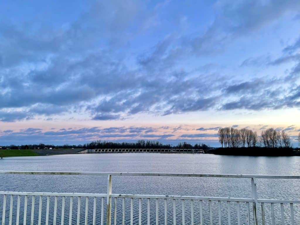 Uitzicht op het Gelders Eiland met water en brug onder een kleurrijke hemel.