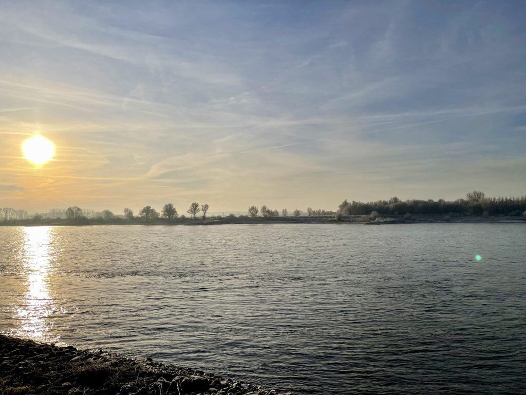 Zonsondergang over de rivier op 't Gelders Eiland, met kalme wateren en een heldere hemel.