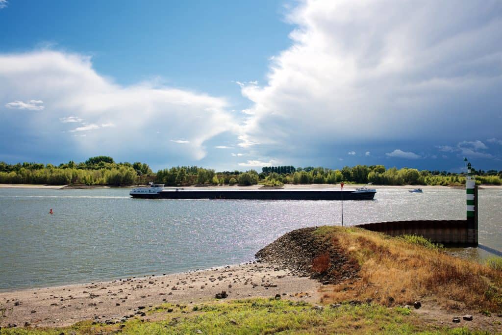 Rivier met een grote scheepvaart en een groene oever op 't Gelders Eiland.