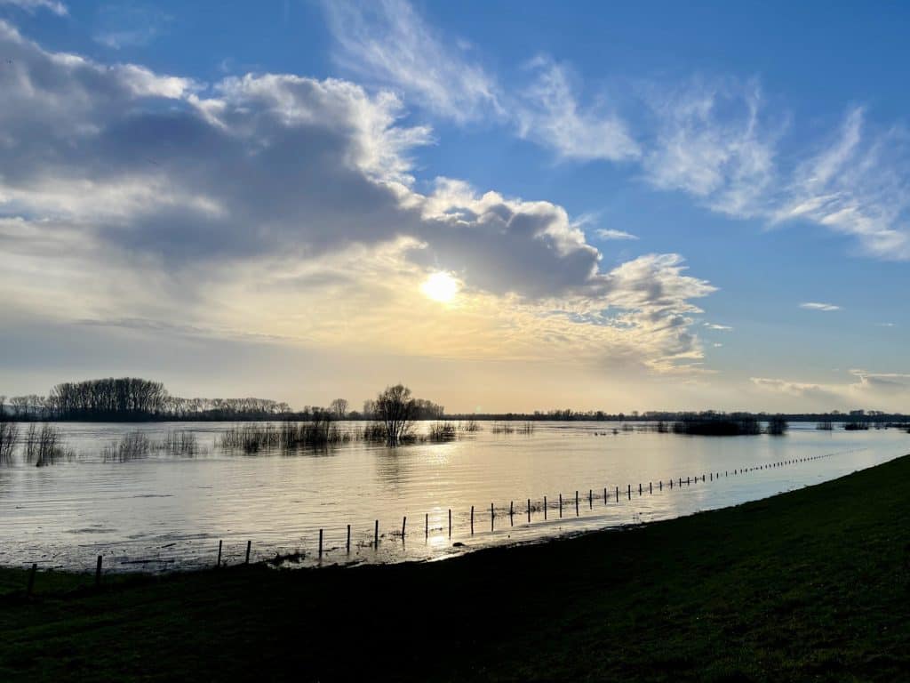 Zonsondergang over de rivier met wolken en reflectie op het water, landschap op 't Gelders Eiland.