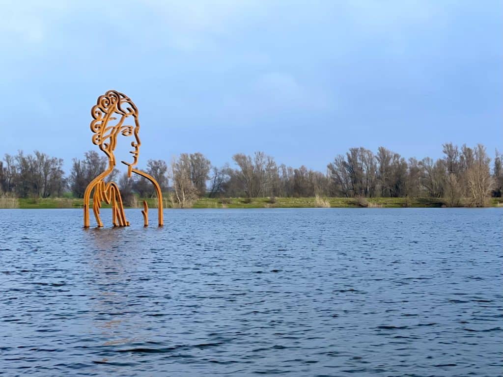 Kunstwerk op water 't Gelders Eiland met een grote metalen sculptuur van een vrouwenhoofd.