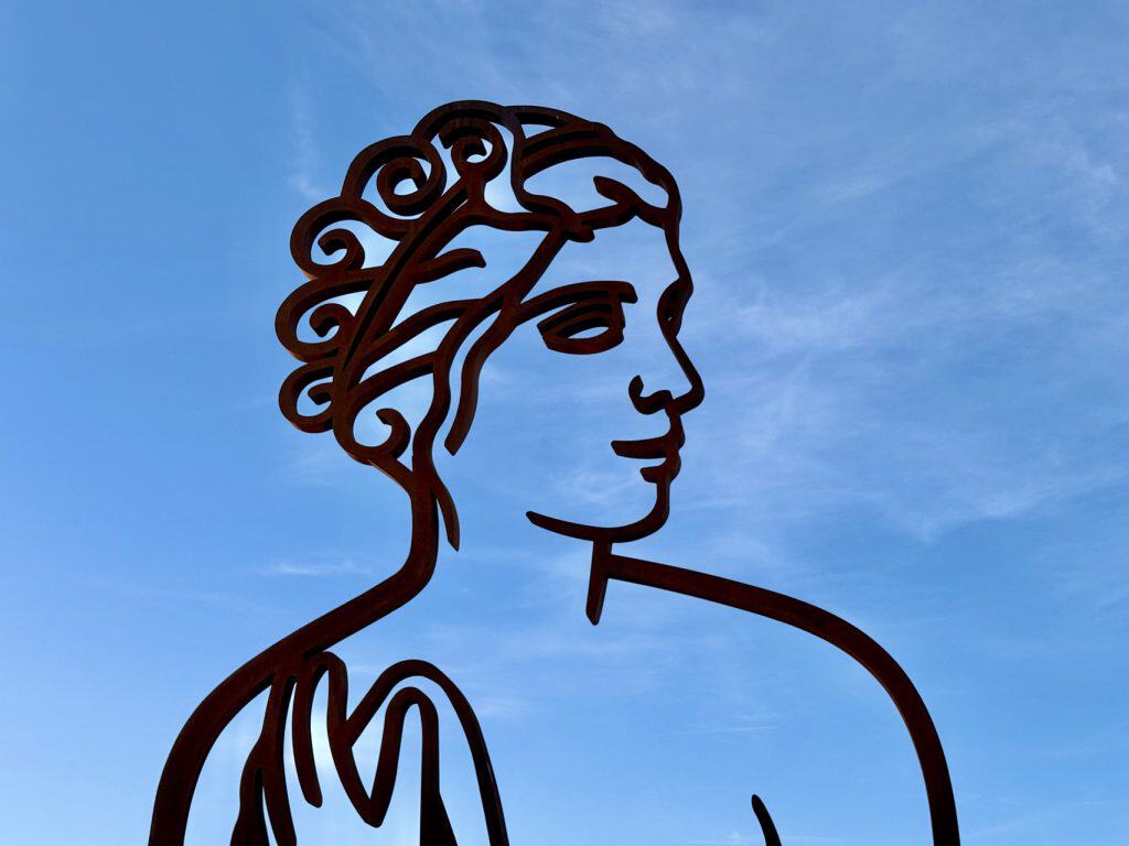 Kunstwerk van een vrouw in zwart lijntekening op blauwe lucht, gelegen op 't Gelders Eiland.